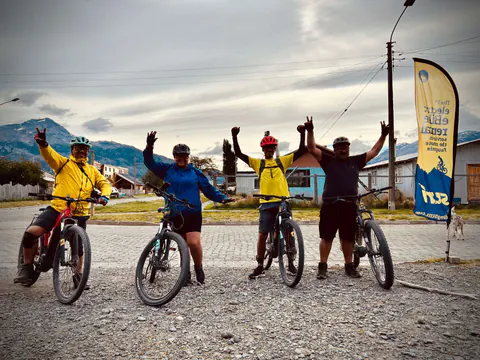 Cuatro riders con casco celebran con los brazos arriba antes de salir, en una calle de Villa O'Higgins