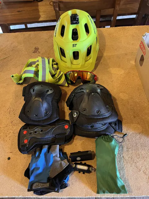 Casco, guantes, rodilleras y coderas sobre una mesa de madera