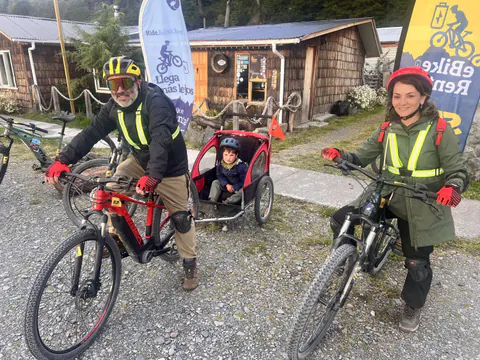 Una familia en e-Bike, con un niño en el carrito, frente al local de SURí