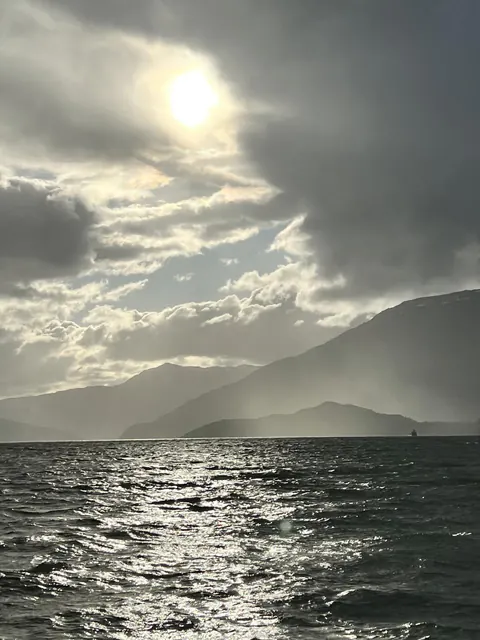 El sol sobre el agua del fiordo Mitchell, entre cerros y nubes