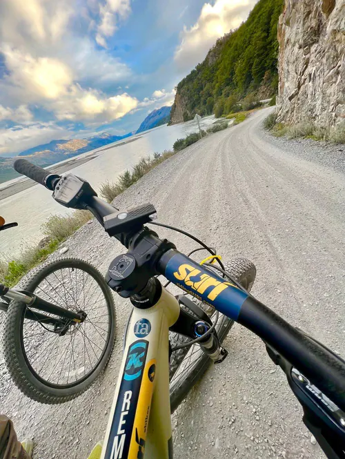 Manubrio de una e-Bike SURí sobre el ripio de la Carretera Austral, junto a un lago